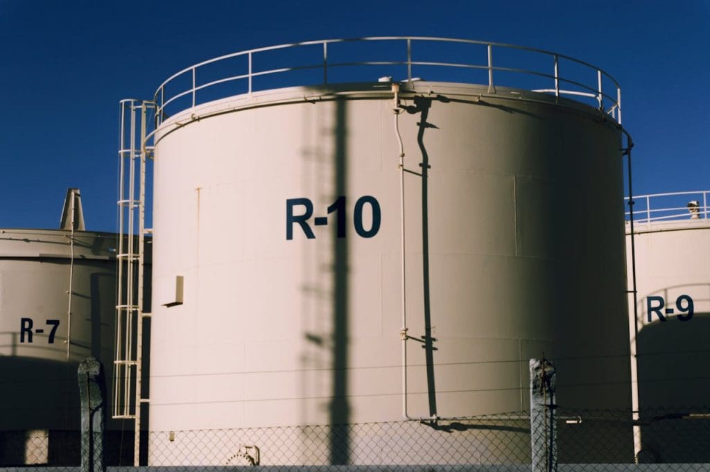 photo-of-white-industrial-containers-17816971 Large industrial storage tanks under blue skies, highlighting metal structures.